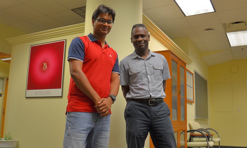 Professor Philip Phillips (right) and graduate student Bikash Padhi pose in the Institute for Condensed Matter Theory on the Urbana campus.&nbsp;