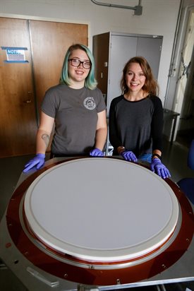 &lt;sub&gt;U of I physics undergraduate student Anna Kofman poses with REU student Sierra Barone from Wheaton College, in the Vieira lab, Summer 2017. In the foreground is a large lens with a specially developed anti-reflection coating for the South Pole Telescope 3G Camera. Kofman is now a graduate student at the University of Pennsylvania. Photo courtesy of Joaquin Vieira, University of Illinois at Urbana-Champaign&lt;/sub&gt;