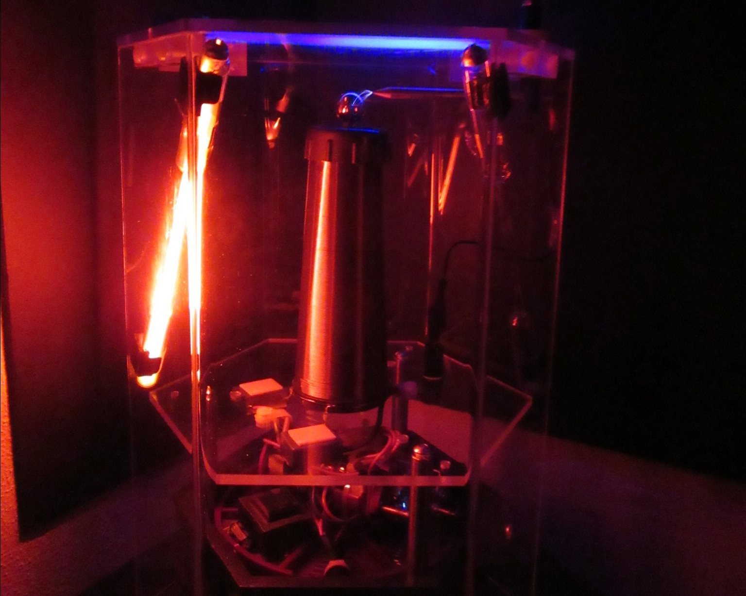 A Tesla coil produces voltages in excess of 50,000 volts that are able to arc through the air (the bright blue spark coming from the metal sphere at the top) and light up neon bulbs that aren&rsquo;t connected in any way. Photo by Paul Kwiat, Department of Physics, University of Illinois at Urbana-Champaign